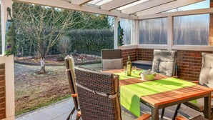 A covered patio with a table, chairs, and a bottle of wine. - Nice home in Schneverdingen with WiFi (Schneverdingen)
