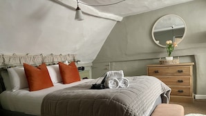 Een slaapkamer met een bed, een dressoir, een spiegel en een hanglamp.