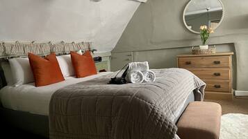 Quarto com cama, penteadeira, espelho e luminária pendente.