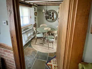 Een eetgedeelte met een ronde tafel, stoelen, een hanglamp en een radiator.