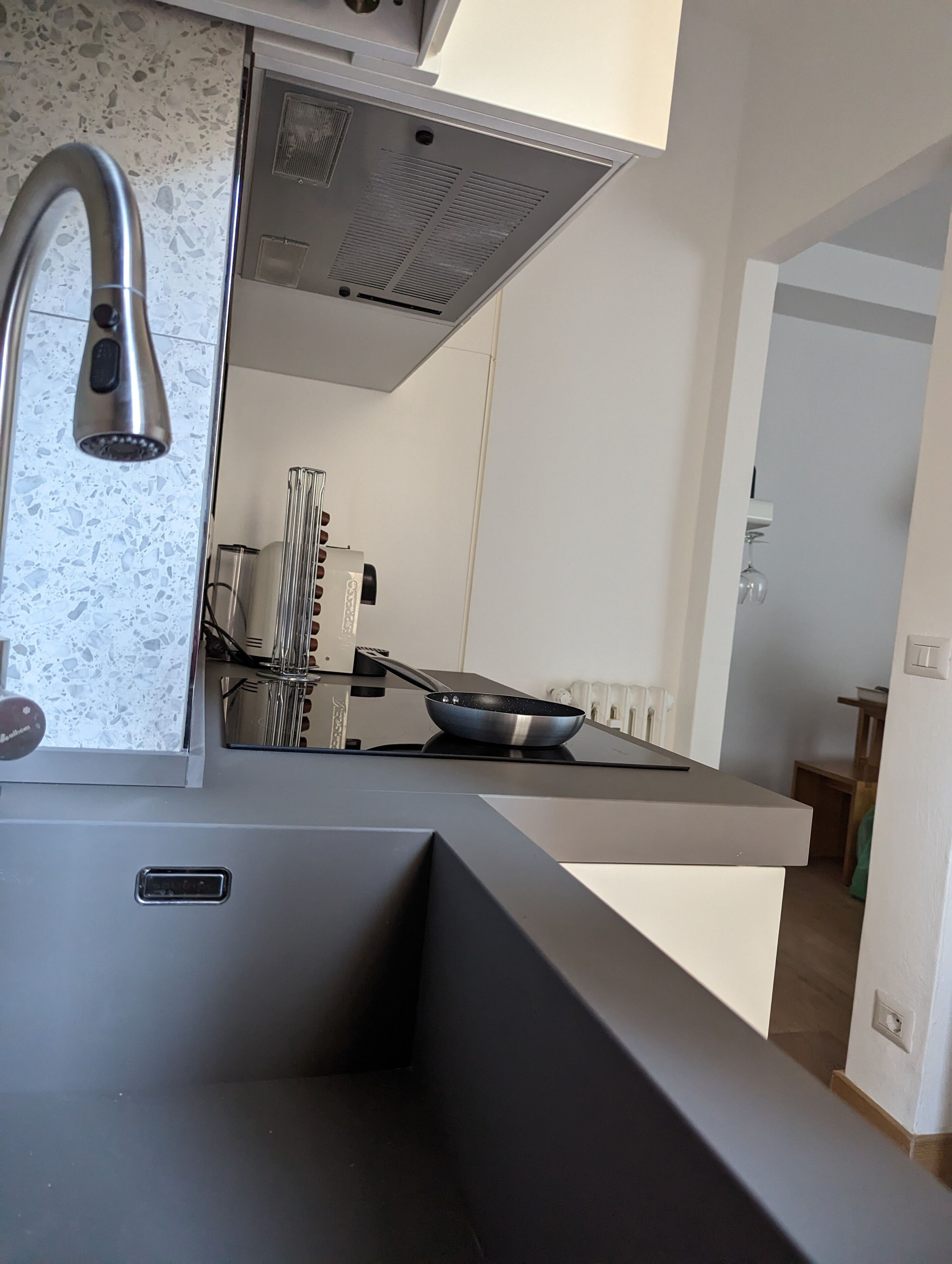 Una cucina moderna con lavello in acciaio inossidabile, piano cottura integrato e schienale decorato con un motivo screziato.