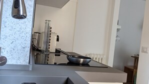Et moderne køkken med vask i rustfrit stål, indbygget komfur og bagplade med et støvet mønster.
