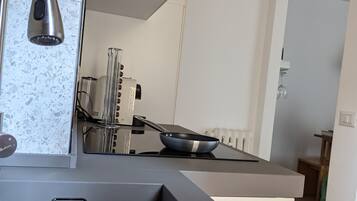 Una cucina moderna con lavello in acciaio inossidabile, piano cottura integrato e schienale decorato con un motivo screziato.