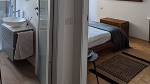 Et moderne soveværelse med seng, sengebord og et spejl på væggen.