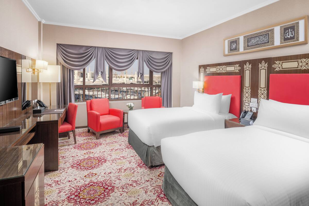 Une chambre d’hôtel avec deux lits, une télévision, un bureau et une chaise.