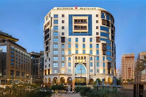 Een hotel met meerdere verdiepingen, een opvallende boogvormige ingang en balkons.