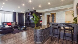 A modern living room with a dark wood floor, a dark sofa with red and patterned cushions, a glass coffee table, and a large window with sheer curtains. - Lovely apartment in Palmi (Palmi)