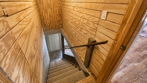 Eine Holztreppe im Innenbereich mit Metallgeländer und einer Tür am Fußende.