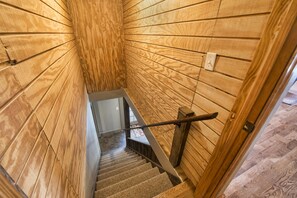 A wooden interior with a staircase, a handrail, and a light switch on the wall.
