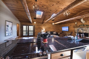 A spacious kitchen with a large island, a stone fireplace, and a dining area with wooden furniture.
