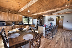 Une cuisine spacieuse avec des meubles en bois, un coin repas doté d’une grande table et de chaises en bois, et une vue sur l’extérieur.