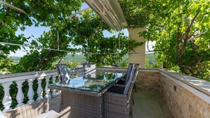 A glass-top table with wicker chairs on a balcony with a stone wall and white balustrade. - Beautiful home in Zaton Obrovacki (Zaton Obrovacki)