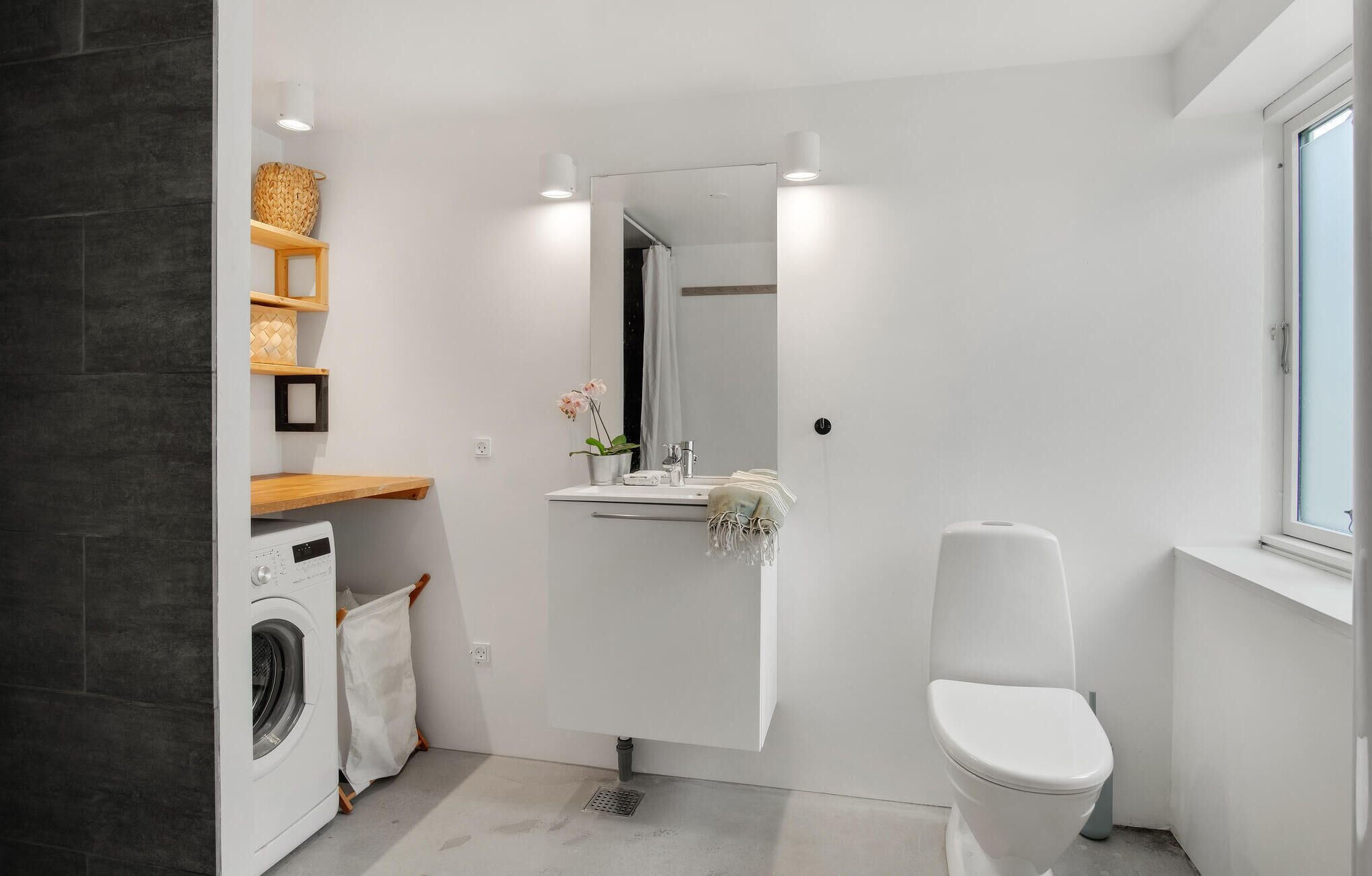 A compact bathroom with a washing machine, a sink with a mirror, and a toilet.