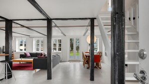 Ein modernes Interieur mit sichtbaren Balken, einem Essbereich und einer Treppe.