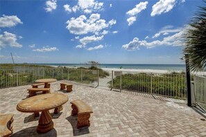 An outdoor patio with a view of the beach, featuring a table and benches.