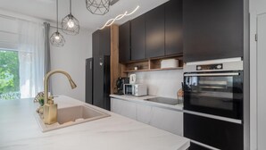 Una cocina moderna con encimera blanca, grifo dorado, horno empotrado y cafetera.
