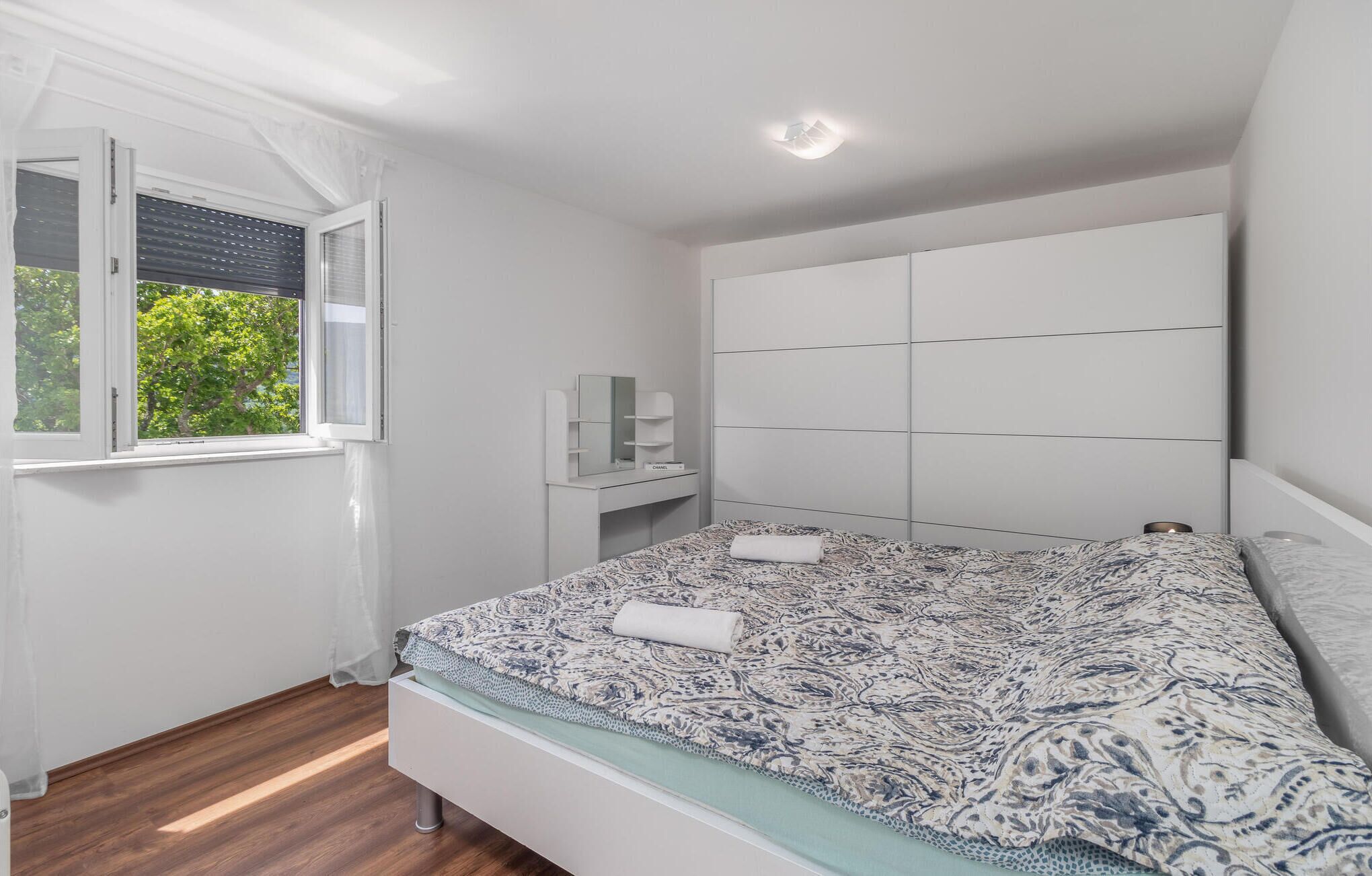 A bedroom with a bed, a window with curtains, a bedside table, and a headboard.