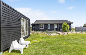 Een modern huis met twee verdiepingen, een donkere gevel en een verzorgd gazon.