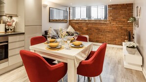 A modern kitchen with white cabinets, a dining table set for four, and red chairs.