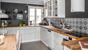 Una cocina moderna con armarios blancos, encimera de madera y salpicadero decorado.