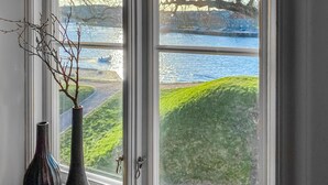 Una ventana con vistas a un río, una colina cubierta de hierba y un puente.