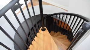 Una escalera de caracol con barandillas negras y escalones de madera.
