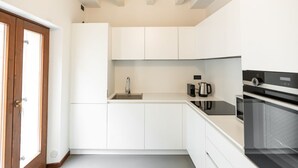 Eine moderne Küche mit weißen Schränken, einer Edelstahlspüle, einer Kaffeemaschine und einem eingebauten Backofen.