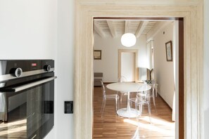 Una cocina con estufa moderna y comedor con mesa redonda y sillas transparentes.