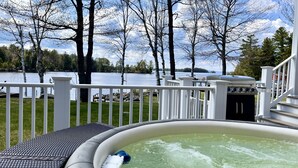 Ein Whirlpool auf einer Terrasse mit Blick auf einen See und Bäume.