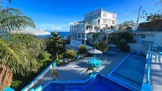 Un hotel con piscina, area salotto all'aperto e vista mare.