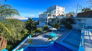 Un hotel con piscina, mobiliario exterior y vista al mar.