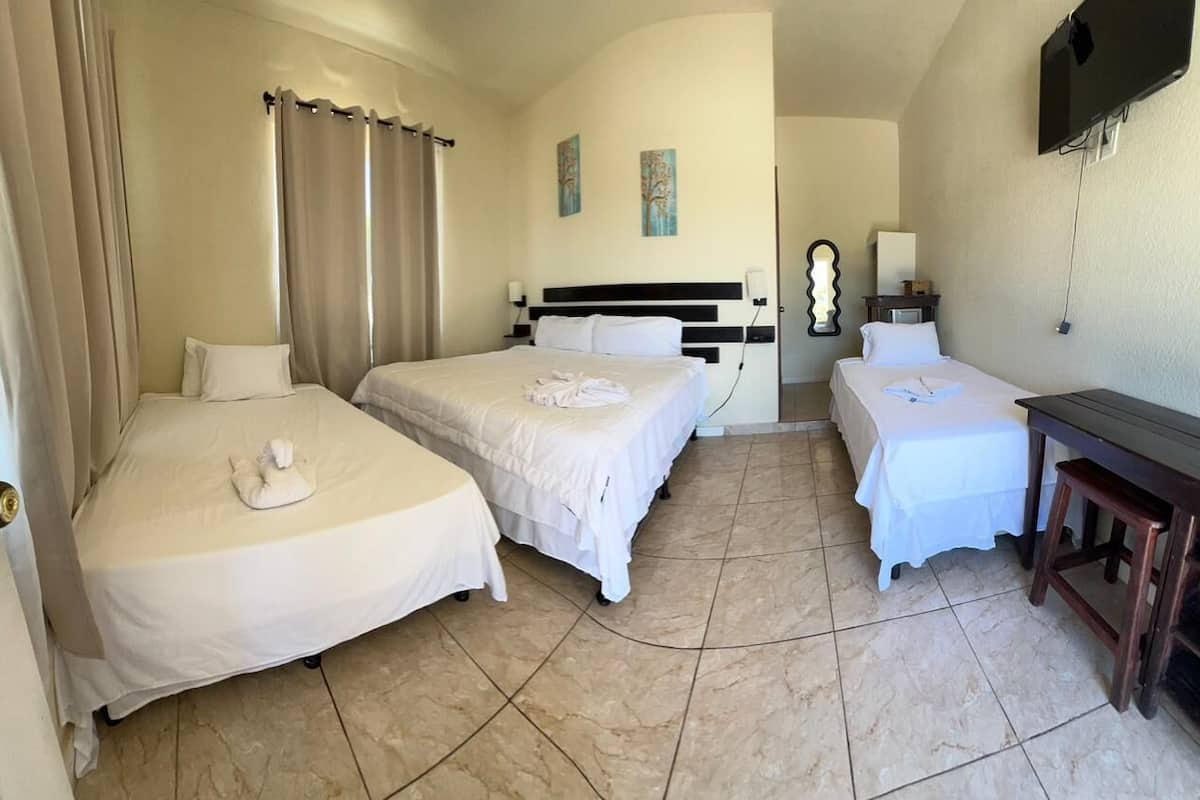 Une chambre d’hôtel avec deux lits, un bureau, une télévision et un miroir dans la salle de bain.