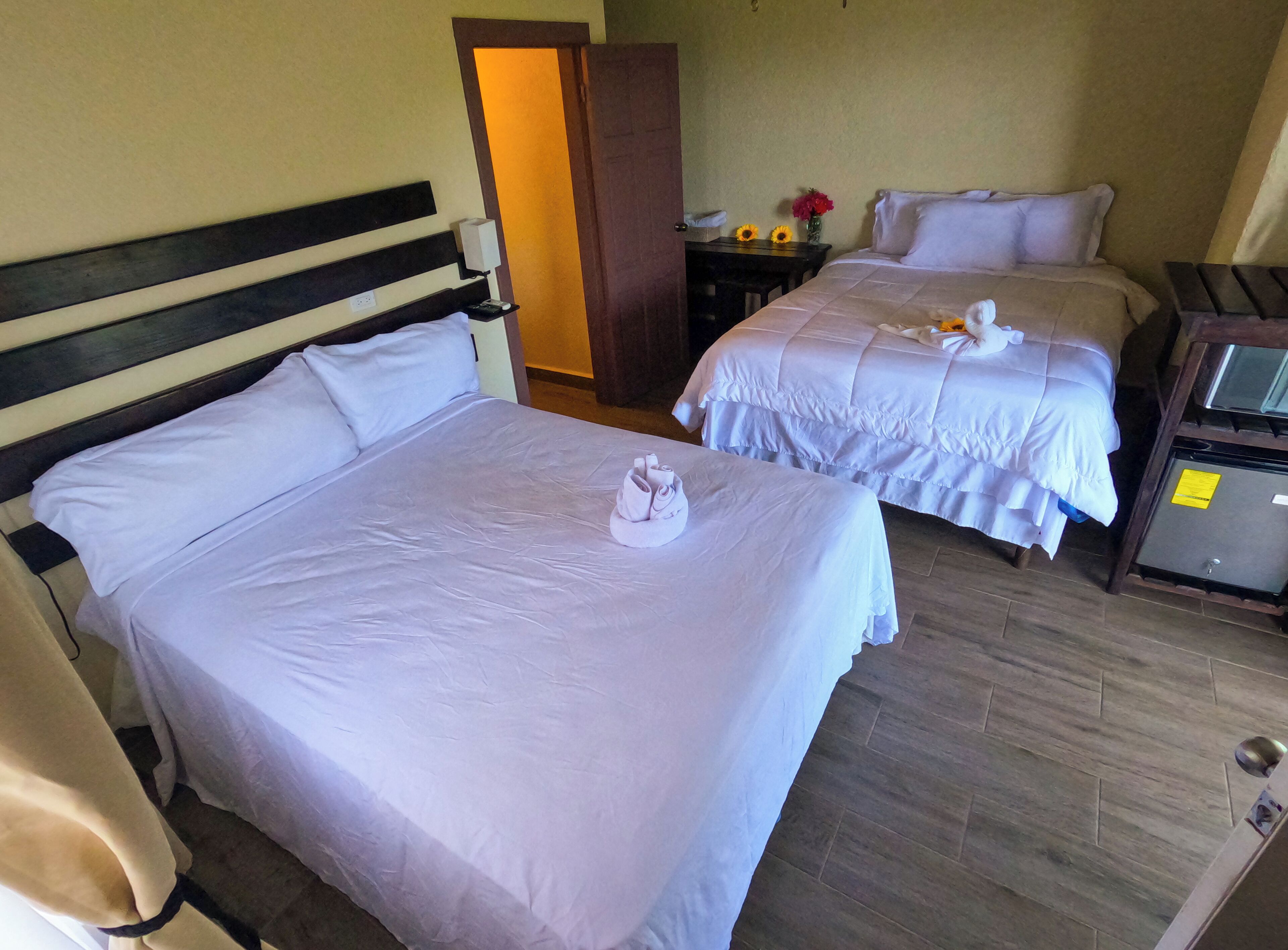 Una habitación de hotel con dos camas, un escritorio con computadora y una caja fuerte.