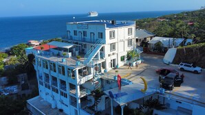 Un hotel a più piani con vista sull'oceano, dotato di piscina, area parcheggio e una scala che conduce ai piani superiori.