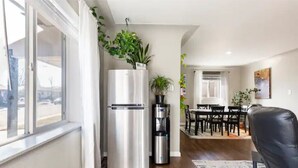 A modern kitchen with a stainless steel refrigerator, a water dispenser, and a potted plant on top.