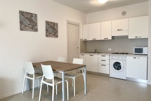 A modern kitchen with white cabinets, a built-in microwave, and a washing machine.