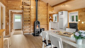 Interior de una cabaña de madera con cocina, comedor y chimenea.