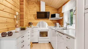 Una cocina moderna con paredes de madera, armarios blancos, una estufa de acero inoxidable y un microondas.