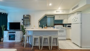 A compact kitchen with white cabinetry, a central island with stools, a built-in oven, and a microwave. - Summertime Bayou Houseboat Oasis: Fish, Hot tub, Kayak (Morgan City)