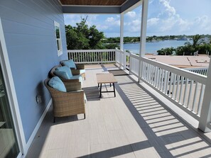 A covered outdoor area with wicker furniture and a view of the water. - Indigo House with private pool, dock slip, & house generator on Green Turtle Cay (North Abaco)