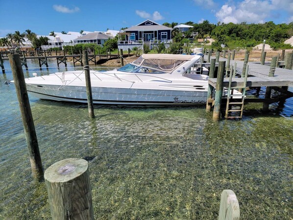 A boat docked at a pier with a house in the background.