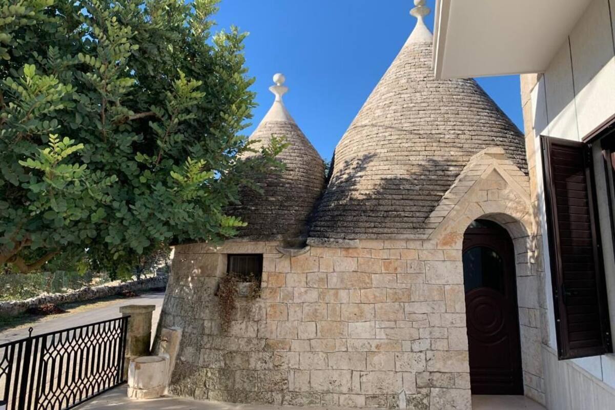 A stone building with three conical roofs and a tree in the foreground.