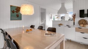 Eine moderne Küche mit Holztisch, weißen Schränken und einer Pendelleuchte.