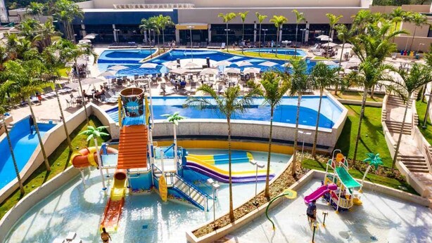 Parque acuático con múltiples piscinas y toboganes, rodeado de palmeras y zonas de descanso.