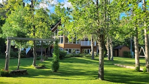 Il s’agit d’une propriété résidentielle dotée d’une pelouse bien entretenue, d’une balançoire en bois et d’une maison à deux étages avec de grandes fenêtres.