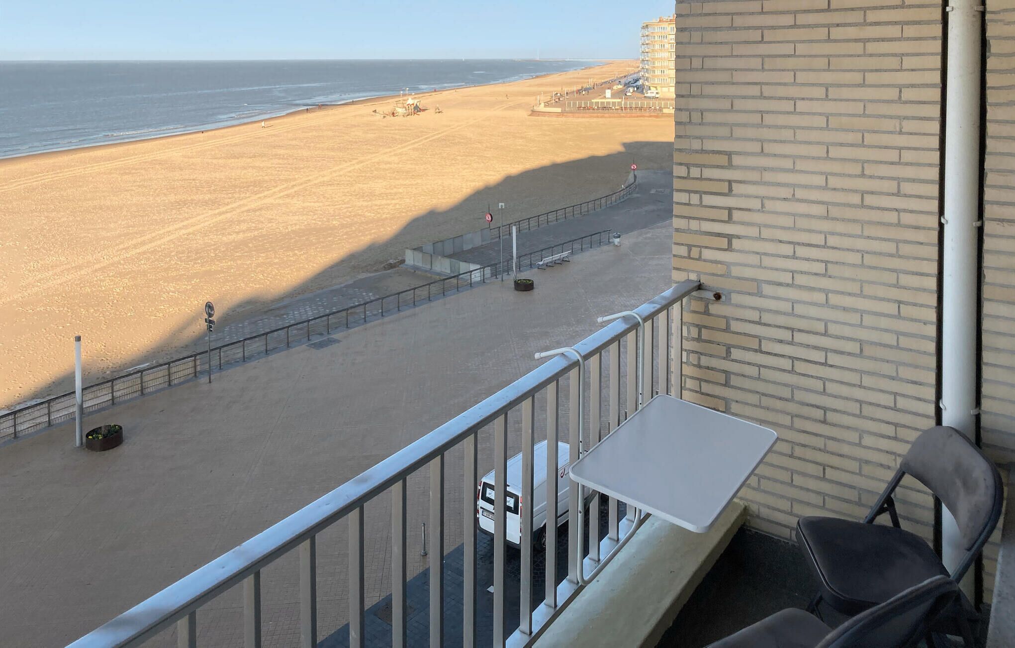 Een balkon met uitzicht op een zandstrand en de oceaan.