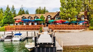 A dock with boats, a wooden pier, and a building with outdoor seating.