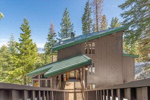 A wooden cabin with a green roof, surrounded by tall pine trees. - Tahoe Views & Tahoe Park Access (Tahoe City)