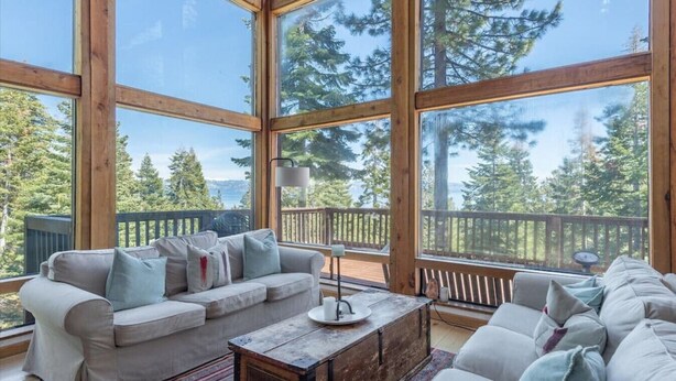 A spacious room with a large wooden-framed window, a beige sofa, and a wooden coffee table.
