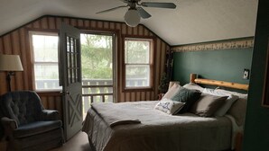 Ein Schlafzimmer mit einem Bett, einem Sessel und einem Fenster mit Jalousien.